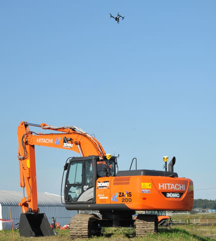 テラドローンと日立建機、他社UTMとの連携飛行デモンストレーションに参加 日立工機の油圧ショベルの上空を飛行するUAV