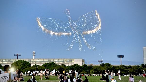 写真：ドローンショーの様子。ドローンの光によって空に表現された火の鳥。翼の先から花火が噴き出している。