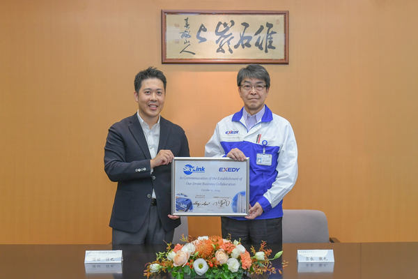 写真：2人が並び、文書の入った額を持つ様子