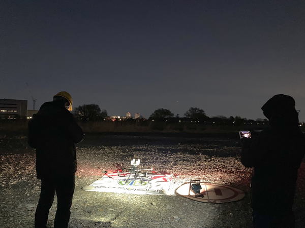 写真：暗い屋外でライトに照らされたドローン