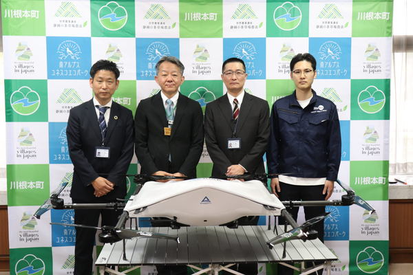 写真：ドローンの後ろに並ぶ4人