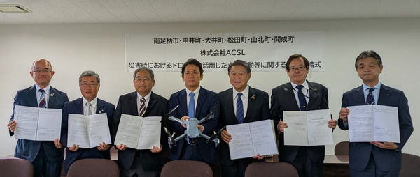 写真：協定書やドローンを手に持つ7人