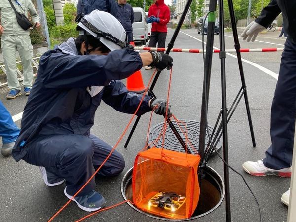 写真：スタッフがIBIS2をマンホールから下水道管内に下ろす様子