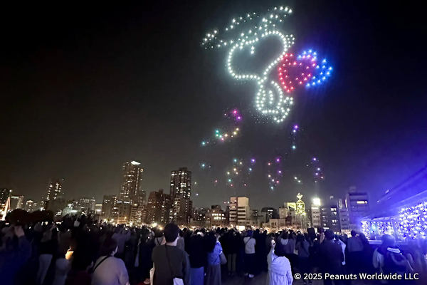 写真：ドローンショーの様子（スヌーピー）、観覧する多くの人々