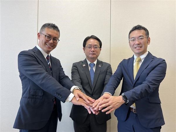 写真:手を重ね合わせる3人