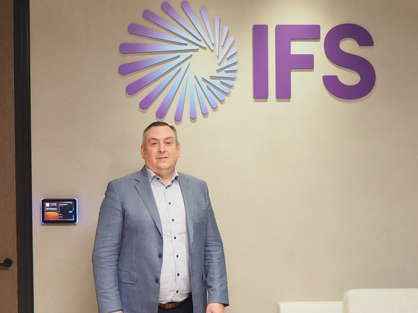 写真：IFSのロゴの前に立つスコット・ヘルマー氏