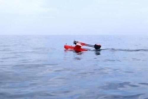 写真：海に着水して移動する赤いUAV