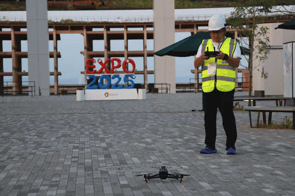 写真：万博会場内の地面でスタンバイするドローン、操縦者
