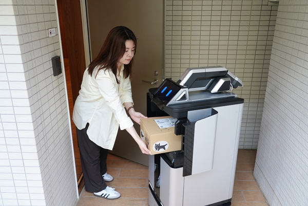 写真：ロボットの扉側が開き、利用者が荷物を出し入れする様子