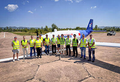 写真：航空機の前に並ぶカワサキモータースとドロナミクス社のチームメンバー
