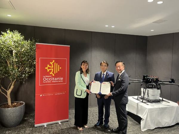 写真：覚書を手にもつ3人、展示されたドローン