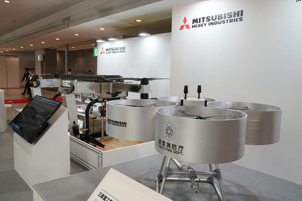 写真：三菱重工のブースに展示された中型無人機と消火活動用ドローン（試作機）