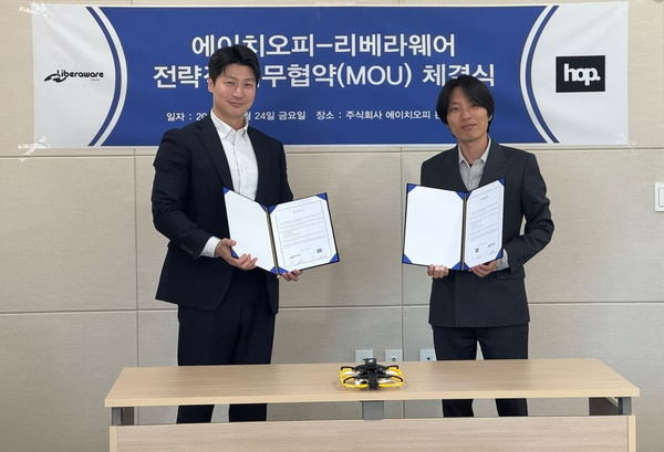 写真:机に置かれたドローン、覚書を手にする2人