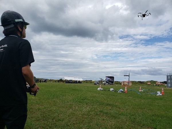 写真：飛行するドローンと操縦者