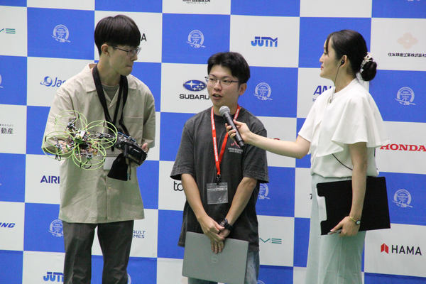 写真：マイクを向けられて話をする学生