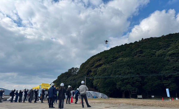 写真：大勢の関係者が見守る中飛行するドローン