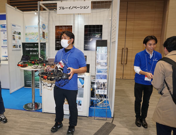 写真：展示ブースでELIOS 3を手に持つスタッフ