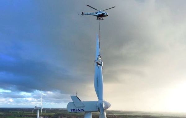 写真：無人ヘリコプター「K-RACER」がロボットを吊り下げてブレードの上を飛行する様子