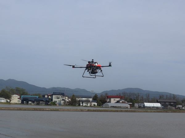 写真:圃場の上を飛行するドローン