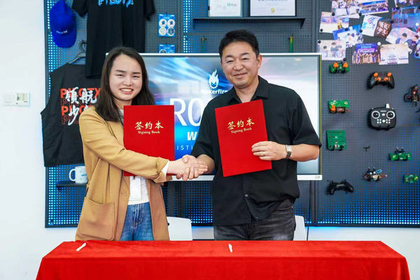 写真:締結書を手に握手を交わす2人