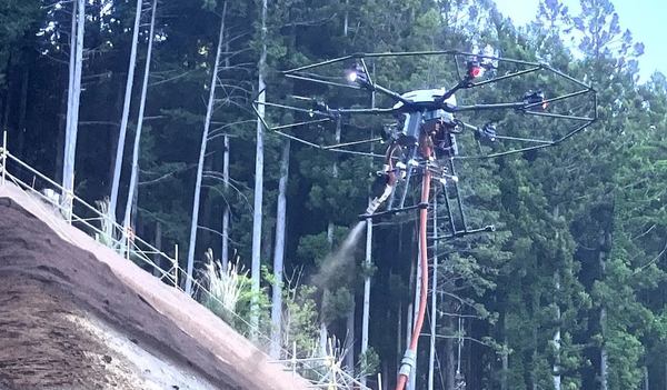 写真：ドローンが法面に人工土壌吹き付ける様子