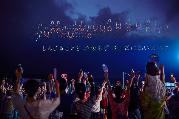 写真：ドローンショーで夜空に描かれた、オロナミンCのビンを音符に見立てた楽譜（KAN「愛は勝つ」）