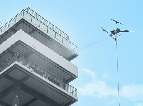 写真:飛行するドローンが建物に向かって放水する様子