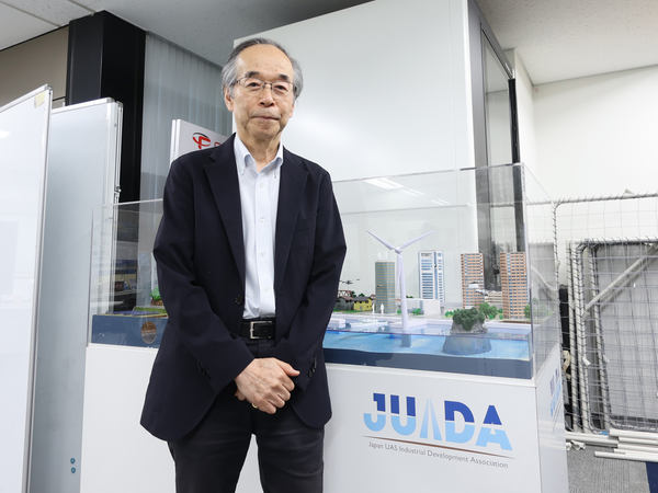写真:模型の前に立つ鈴木氏
