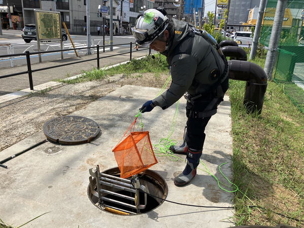 写真：マンホール内にドローンを入れたネットを下ろす様子
