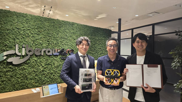 写真：バッテリー、ドローン、意向書をそれぞれ手にする3人