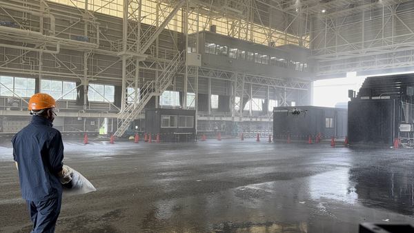 写真:建物内で再現された暴風雨環境の中を飛行するドローン、操縦士